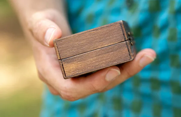 Man holding a small simple generic wooden box container in hand, detail, closeup, mystery gift box, presents and gifts. Box for small objects, storage abstract concept, one person. Storing valuables