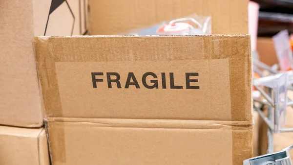 An open brown cardboard box with a FRAGILE label printed on it, opened carton container with a fragile contents materials inside. Print marking, nobody transporting mailing sending easy to break items