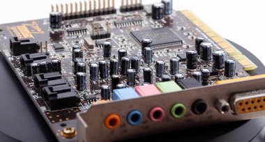 Detailed close-up of an old desktop PC sound card with its electronic components exposed, capacitors resistors, and color-coded audio input output jacks, old PC parts clipart