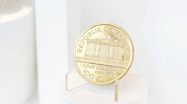 Pure gold coin, Republic of Austria, engraved inscription 1 Unze Gold 999.9 on a small stand, 100 euro worth, high purity and value, precious metals investments clipart