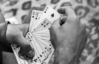 Siyah-beyaz dramatik yakın plan oyun kartları yayılmış, poker, kumar bağımlılığı basit soyut konsept sembolü, isimsiz bir kişi, sosyal meseleler, kapanış detayları.