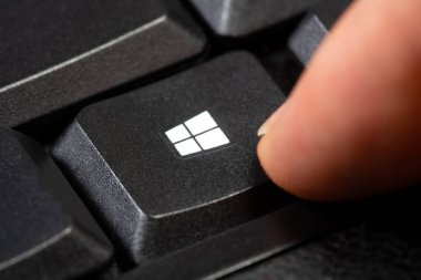 Siyah bir bilgisayar klavyesindeki Windows logosuna parmak basmak makro detay, aşırı yakın çekim, bir kişi. Microsoft Windows 10 ve 11 işletim sistemleri kavramı