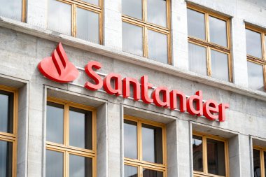 Şehir merkezine gömülü modern bir banka şubesinin ön cephesinde Red Santander banka logosu. Haber çekimi, İspanyol Santander şirketi konsepti, logo yakın plan.