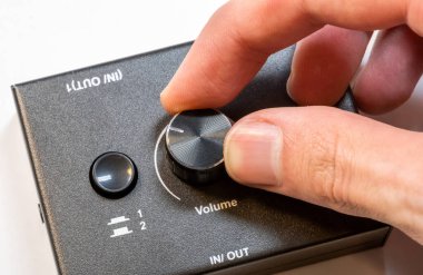 Modern bir ses cihazının ses düğmesini ayarlayan bir adamın elinin yakın çekim görüntüsü. Ses çıktısını daha sessiz ya da daha yüksek sesle basit bir konsept haline getirmek, tek bir kişi, detay çekimi. Ses aygıtları kullanımı