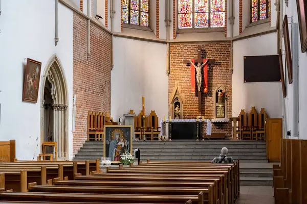 Yalnız bir adam, Polonya 'nın Wroclaw şehrindeki St. Adalberts Kilisesi' nde haç ve renkli camlarla dua ediyor. Kosciol sw. Wojciecha iç mimarisi