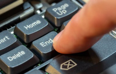 Man pressing the End key on a laptop computer keyboard, finger closeup, one person. Ending an activity, finishing work or a task, leaving, putting an end to something abstract concept, symbol clipart