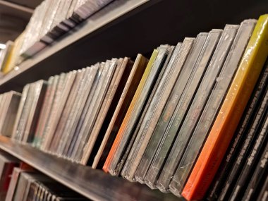 Bir mağazadaki rafta bir sürü farklı müzik CD 'si var. Yakın plan, hiç kimse, sığ DOF. Yasal olarak müzik albümleri alıp satma, CD şarkı albümü dağıtım kanalları