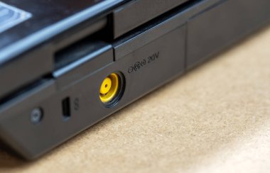 Laptop detaylı yakın plan çekimde kullanılan genel sarı 20V güç adaptörü girişi, hiç kimse, sığ DOF. Fişi çekilmiş güç adaptörü, boş kullanılmamış pil şarj portu. Basit bir konsept.