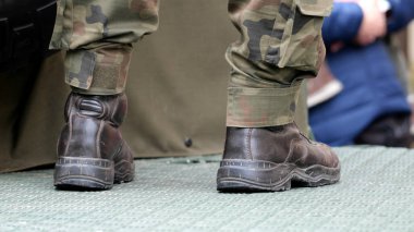 İsimsiz asker bacakları, yakın plan botlar, kamuflaj üniformaları, askeri bir aracın arkasında durmak, detaylı çekim. Avrupalı Amerikan piyade askerleri basit soyut konsept sembolü, haber çekimi