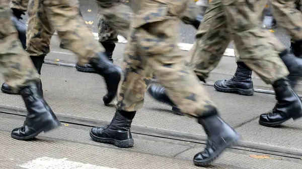 Anonim ordu askerleri sokaklarda kamuflaj üniformaları ve siyah botlarla yürüyorlar, genel dinamik haber çekimi, bir grup insan, yakın plan, hareket, piyade harekatı, askeri geçit töreni...