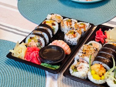 Bir sürü renkli suşi, soya soslu, wasabi, zencefil ve süslenmiş siyah tepside dekoratif masa düzeninde, ev yemeği siparişi konsepti, Japon mutfağı konsepti, bir sürü suşi.