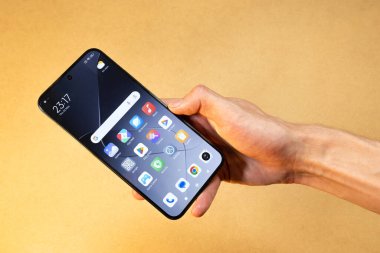 Yeni bir Xiaomi android akıllı telefonu tutan bir adam. Ana ekran ekranı, öntanımlı uygulamalar görünür, yeni cep telefonu satın alma konsepti, basit arka plan, yakın plan.