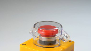 Kırmızı endüstriyel acil durum durdurma düğmesi koruyucu kapaklı, acil durum makinesinin kapatılması için güvenlik anahtarı, panik düğmesi kapanması, nötr arka planda izole edilmiş. Nükleer silahlar düğmesi