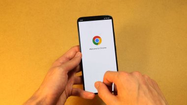 Google Chrome tarayıcı sistemi, elinde tutulan modern akıllı telefon ekranlı cep telefonuyla, logo mobil internet tarayıcı konsepti olan hoş geldin ekranının yakın görüntüsünü başlatıyor.