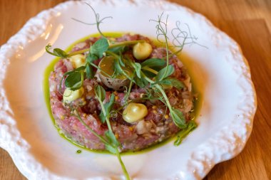 Bıldırcın yumurtası sarısı, hardal, aioli ve yeşillik kaplı tartar beyaz seramik tabakta zeytin yağıyla kaplanmış gurme restoran aperatifi, yakın çekim makro yemek sunumu insan yok, kalite yok.