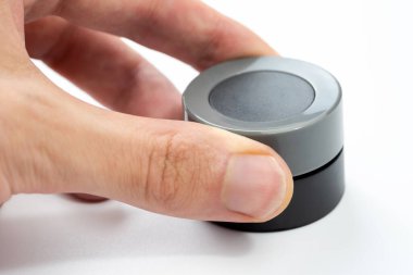 Modern yuvarlak gri kontrol düğmesini ayarlayan parmak, beyaz üzerinde izole edilmiş, insan elinin yakın plan görüntüsü, basit bir yuvarlak arama, genel elektronik cihaz ayarları, ses kontrol arayüzü kavramı