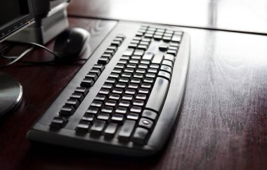 Siyah ofis klavyesi ahşap bir masa üzerinde bir fare ve basit teknoloji konsepti için ergonomik bir bilgisayar klavyesine sığ bir çalışma alanı derinliğinde monitör