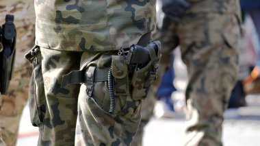 Açık hava devriyesi sırasında tabanca kılıfında tabancası olan, kamuflaj üniformalı isimsiz bir asker, yakın çekim taktikleri, kamuflaj pantolonları ve ekipmanları, askerlerin güvenlik ve savunma hazırlıkları.