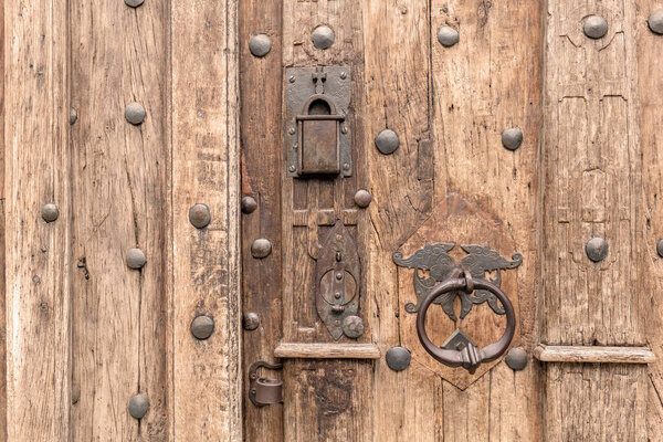 Крупный план старинной старинной деревянной двери с декоративной металлической ручкой и выветренной поверхностью средневековых ворот здания, исторического церковного замка, деревенских текстурированных досок стальных шипов