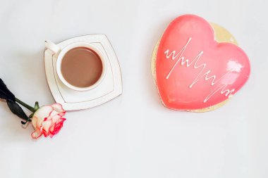 Pembe çay, kalp şeklinde pembe kremalı pasta ve bir fincan kahve..