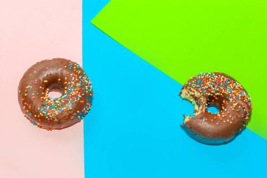 Donuts with chocolate glaze and colored sprinkles of round shape on a colored background