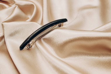 Altın sarısı ipek arka planda zarif siyah saç tokası..