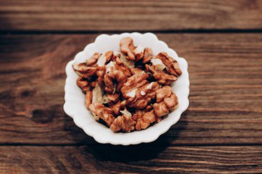 Dried walnut grains in a bowl on a wooden table.