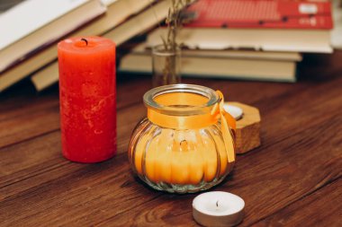 Still life with skins, Orange aroma candle in a figured candlestick with a bow and books on the background.