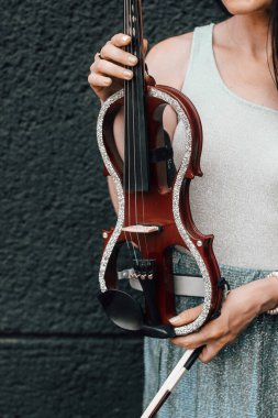 A fragment of an electric violin, a violin in the hands of a musician's girl