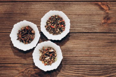 Spices anise, pepper, cumin, cumin, ginger in bowls on a wooden table.