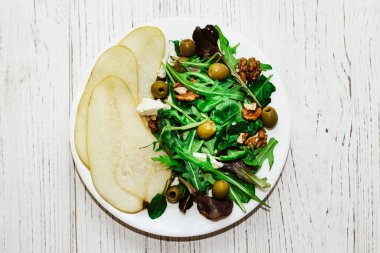 Armutlu salata, otlar, roka, prosciutto, peynir, yeşil zeytin ve fındık..