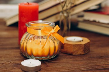 Still life with skins, Orange aroma candle in a figured candlestick with a bow and books on the background.