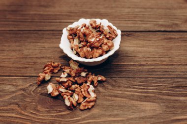 Dried walnut grains in a bowl on a wooden table.