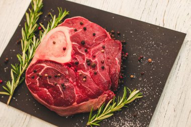 Taze et. Kemik ossobuco 'sunda büyük bir biftek. Siyah arka planda bir filiz biberiye..