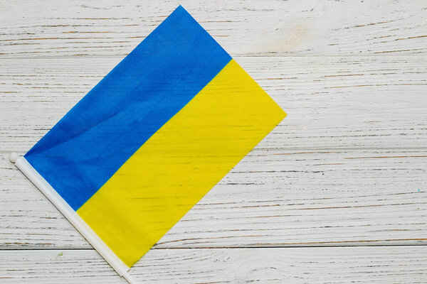 Ukrainian blue yellow flag on a wooden white background.