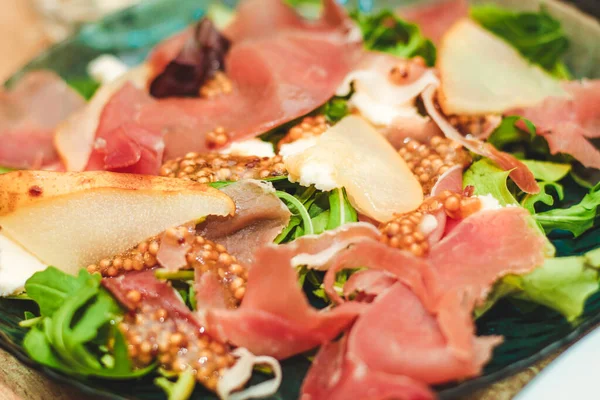 stock image Salad with herbs, arugula, prosciutto, cheese, green olives and nuts.