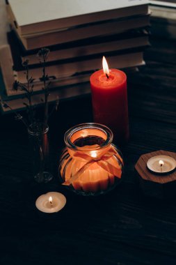 Still life with skins, Orange aroma candle in a figured candlestick with a bow and books on the background.