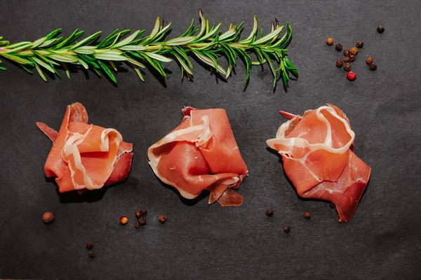 黒ボード上のローズマリーと乾燥豚肉のジャモンプロシクトの作品 — ストック写真