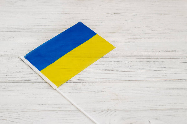 Ukrainian blue yellow flag on a wooden white background.