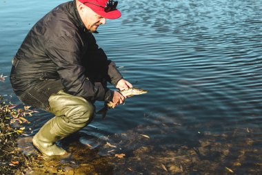 Balıkçı, yakalanan turna balığını nehre geri bırakıyor..