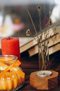 Still life with skins, Orange aroma candle in a figured candlestick with a bow and books on the background.