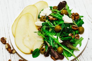 Armutlu salata, otlar, roka, prosciutto, peynir, yeşil zeytin ve fındık..