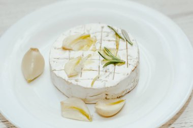 Camembert küflü yuvarlak peynir, biberiye filizi, masada sarımsak..