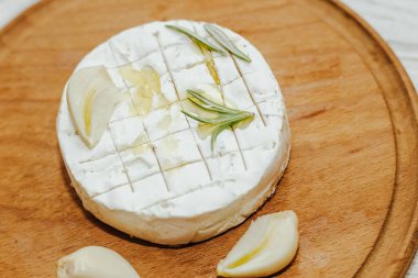 Camembert küflü yuvarlak peynir, biberiye filizi, masada sarımsak..