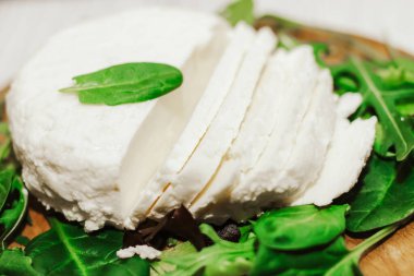 Sülüguni ahşap bir tahtanın üzerinde otlarla peynir turşusu kurdu..