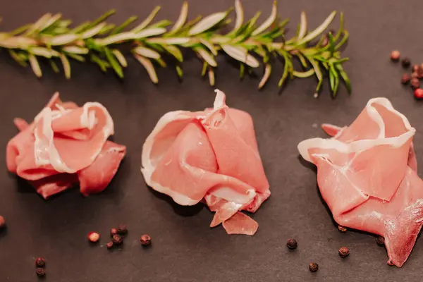 黒ボード上のローズマリーと乾燥豚肉のジャモンプロシクトの作品 — ストック写真