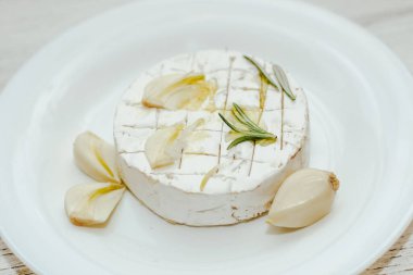 Camembert küflü yuvarlak peynir, biberiye filizi, masada sarımsak..