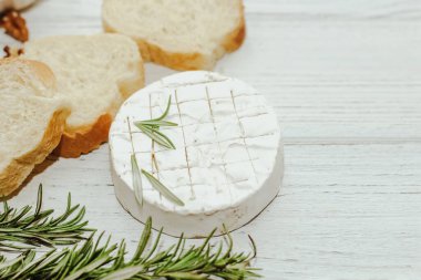 Masanın üzerinde biberiye, bal ve fındık filizi olan camembert küflü yuvarlak peynir.