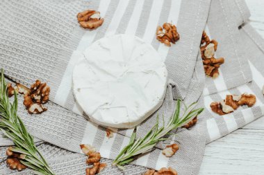 Masanın üzerinde biberiye filizi olan camembert küflü yuvarlak peynir..