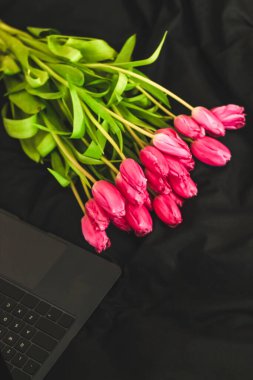 Bir buket pembe çiçek ve açık bir dizüstü bilgisayar.